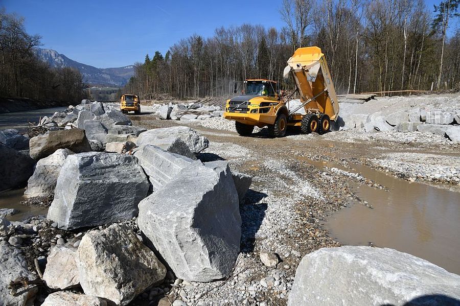 Dumper kippt Wasserbausteine am Ufer der Emme