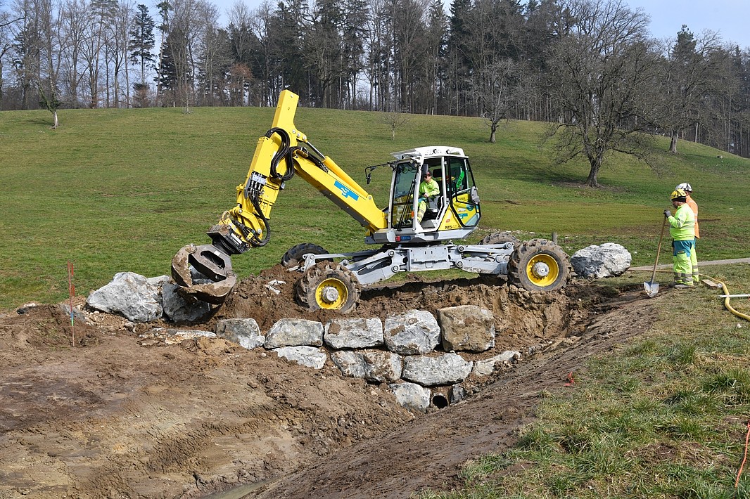 Menzi Muck beim Steine Setzen im Zulauf