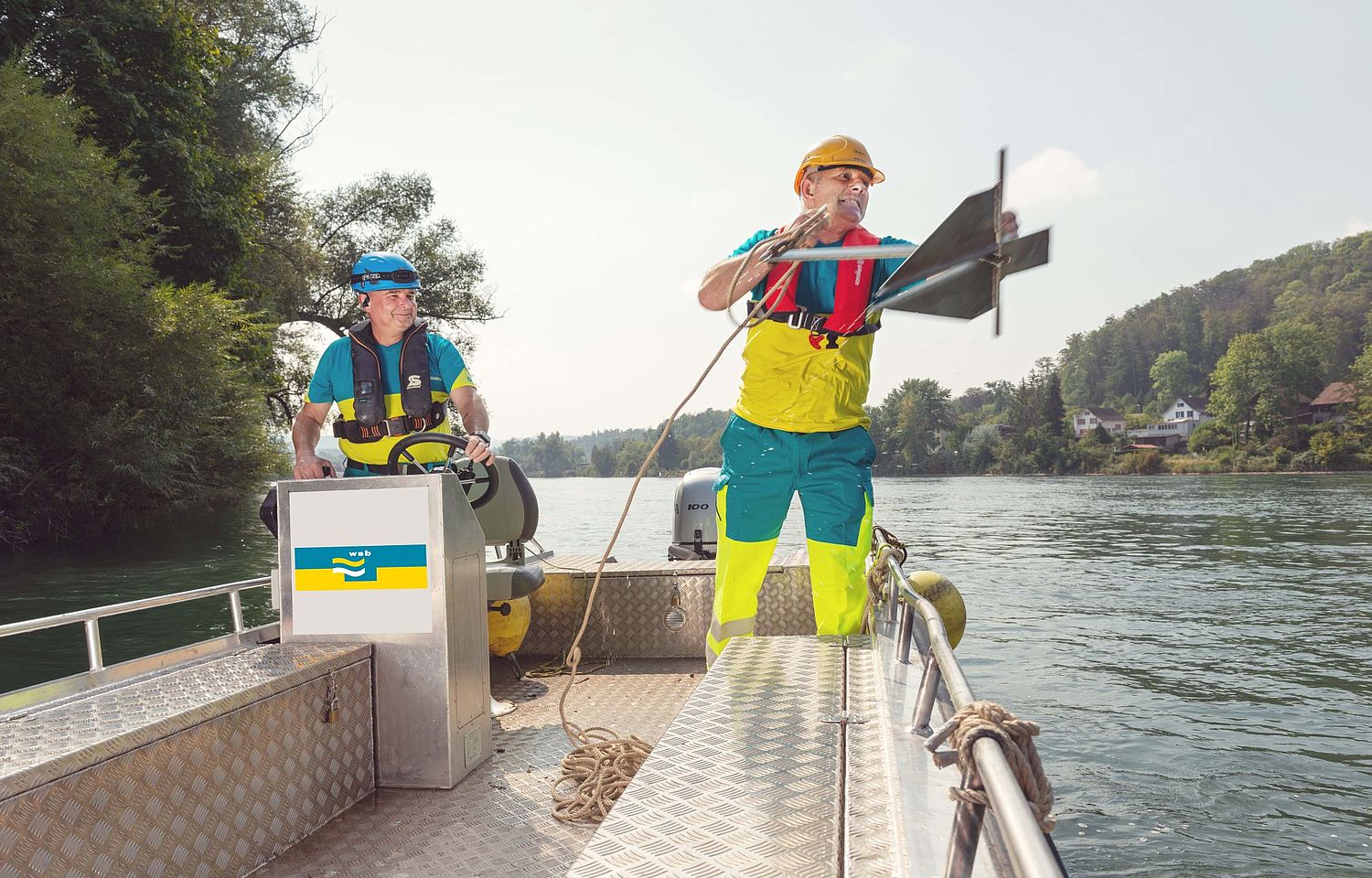 Zwei Mitarbeitende auf einem Boot. Einer wirft den Anker ins Wasser.